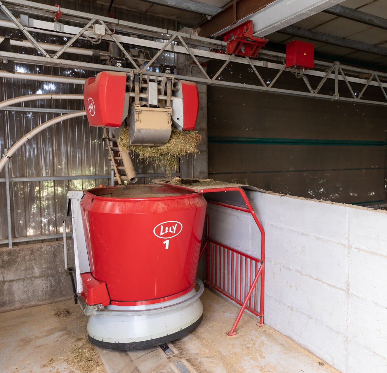 Ένας συλλέκτης ζωοτροφών Lely Vector σε έναν αχυρώνα με διαφορετικούς τύπους ζωοτροφών στοιβαγμένους ο ένας πάνω στον άλλο.